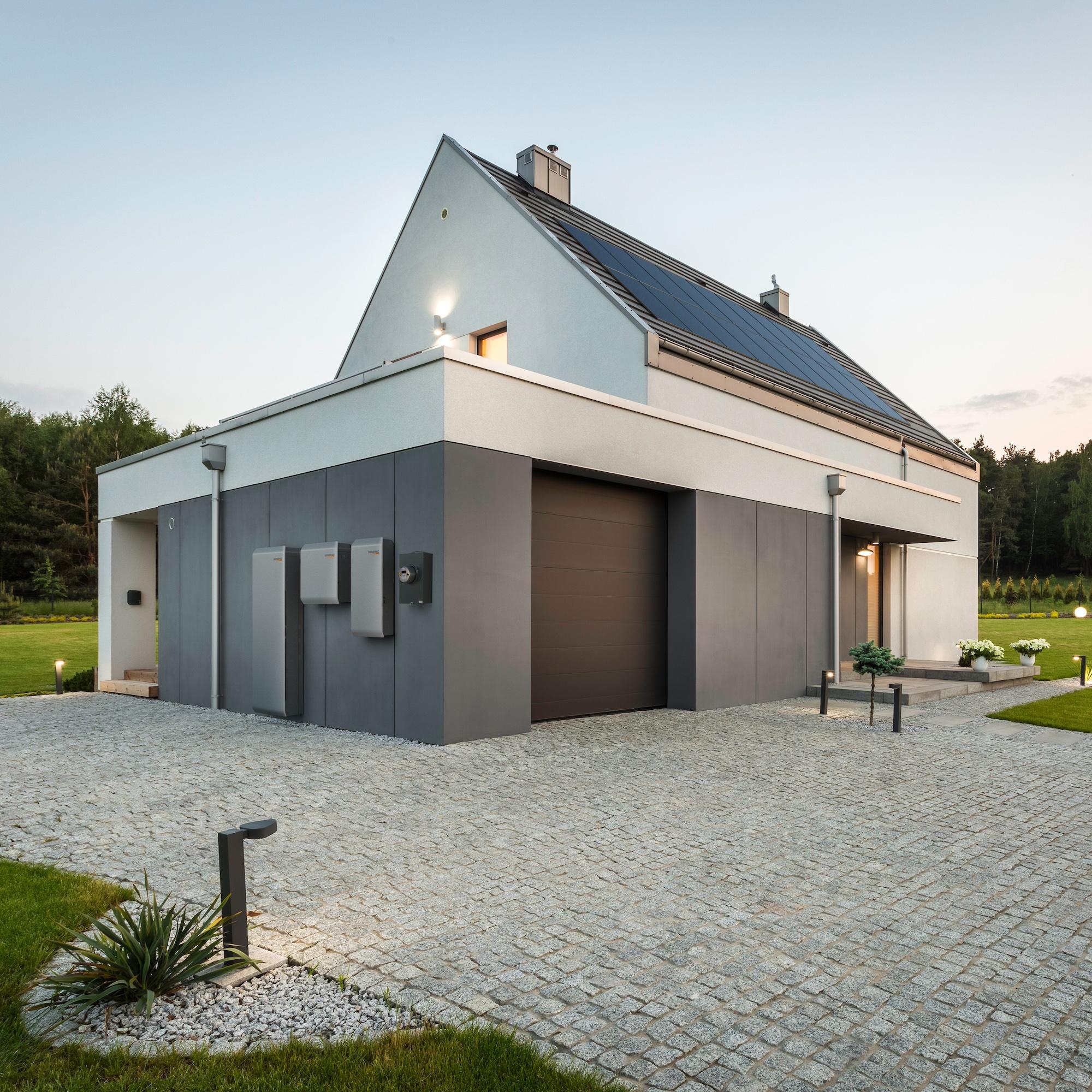 A home at dusk with rooftop solar and wall-mounted Generac PWRcell battery modules.